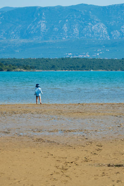 istock Little boy exploring the beach at low tide with a scenic landscape as background - Soline, Krk, Croatia 1180623864