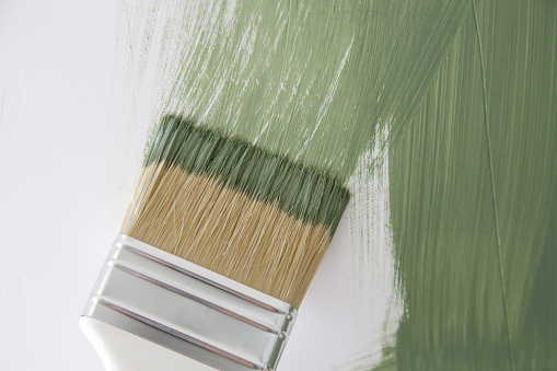 Process of painting wall with green color, paintbrush close up, DIY house improvement project