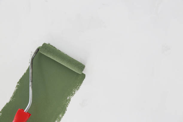 istock Paint roller. Process of painting with green paint over a white wall. 1180625972