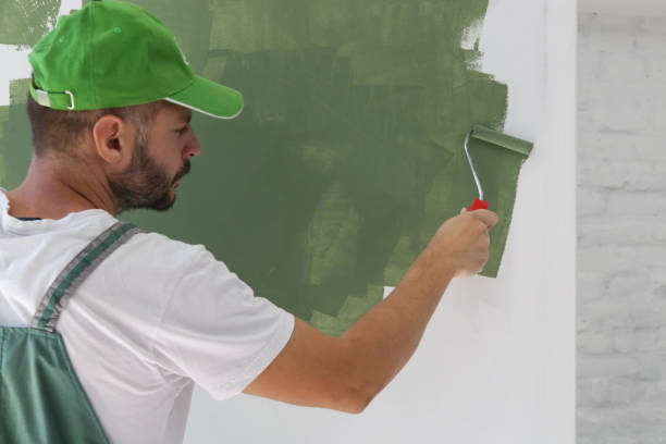 istock Man painting with green paint over a white wall 1180626419