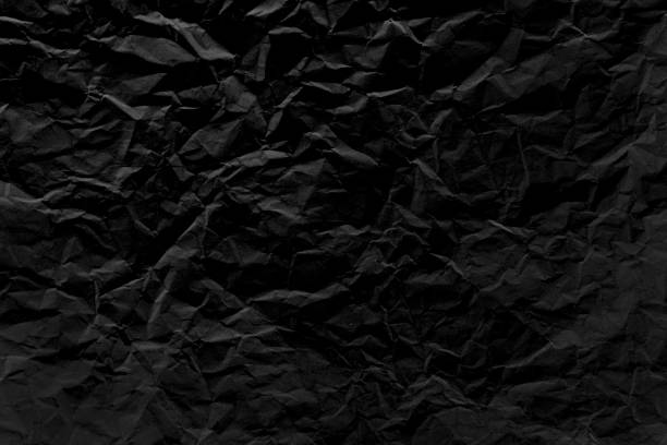istock Old crumpled texture black cardboard sheet of empty paper black background. 1180628886
