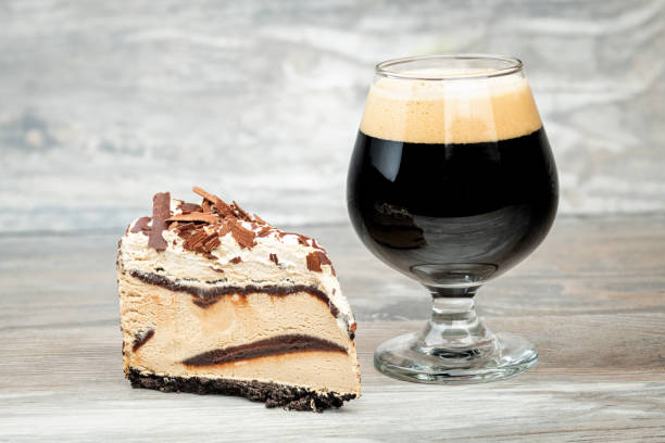 Fancy glass with beer next to a large slice of ice cream cake stock photo
