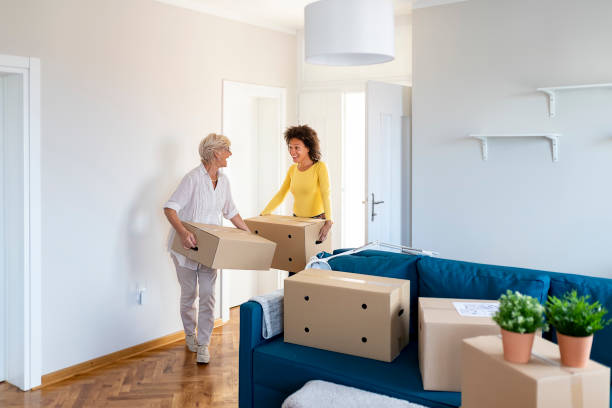 First Time Home Buyers Happy Senior Mother and Adopted African American Daughter With Cardboard Boxes in New House at Moving Day. First Time Home Buyers. seniors-moving-house stock pictures, royalty-free photos & images
