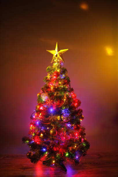 istock Christmas tree with festive lights, orange background 1180638168