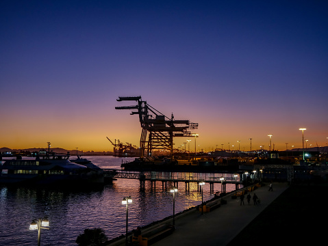 Seaport in Oakland California during sunset with Ferry and cranes