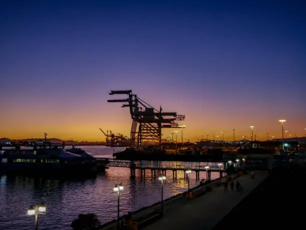 Seaport in Oakland California during sunset with Ferry and cranes