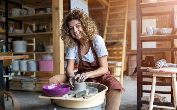 donna che fa lavori in ceramica con la ruota del vasaio - potter small business pottery happiness foto e immagini stock