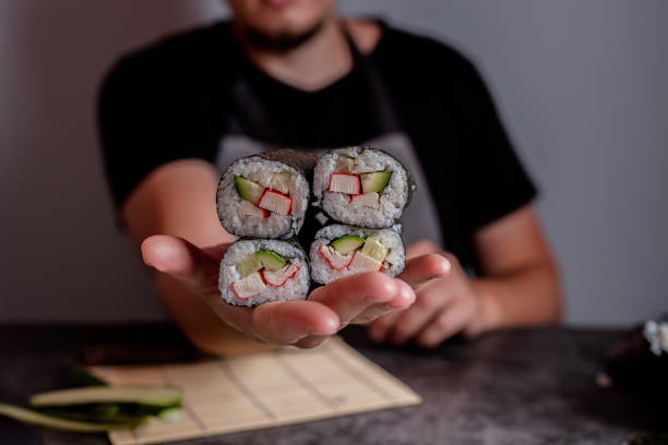 man in the apron holding pile od homemade sushi rolls on dark background - japanese cuisine temaki sashimi sushi imagens e fotografias de stock