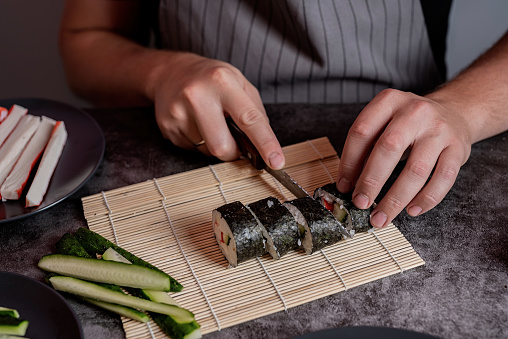 Man hands making homemade sushi rolls with crab meat and vegetables