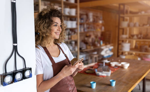 istock Female potter with smartphone in art studio 1180661872
