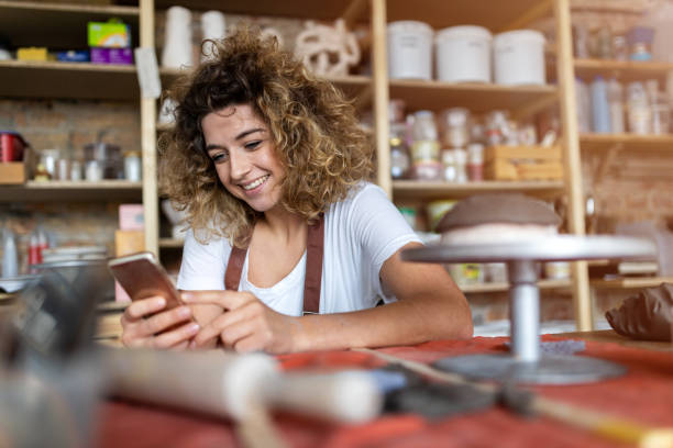 istock Female potter with smartphone in art studio 1180662018