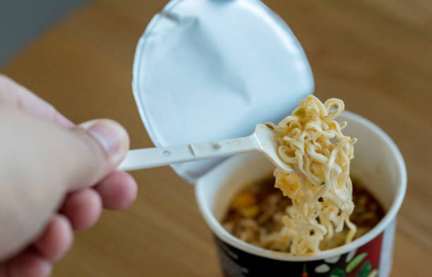 istock Hot noodle Cup. Noodle cup Ready made. Eating Instant Noodles with a Plastic Fork. Junk food Instant noodles are eating the popular food. 1180662902