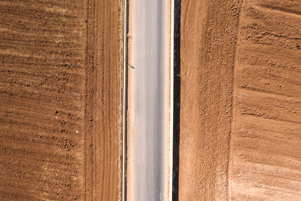 istock Asphalt road with deep brown soil on both sides, Top down aerial image. 1180669671
