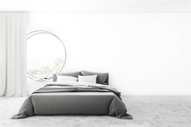 istock Minimalistic white bedroom with round window 1180671814