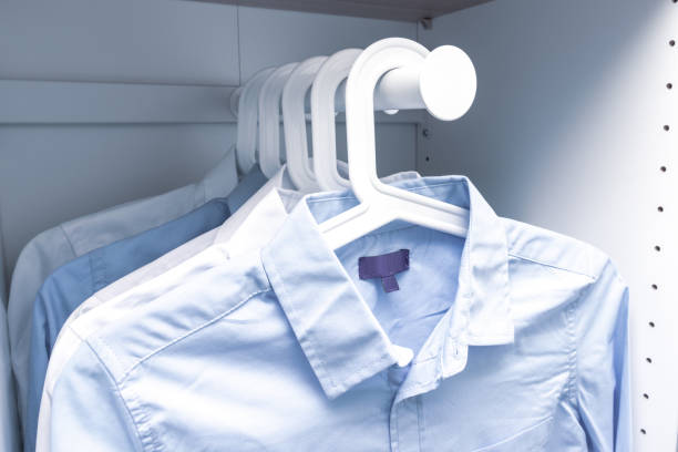 istock Blue and white classic man's shirts on hangers in a wardrobe 1180673053