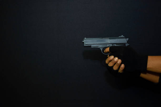 istock asian man holds a gun. Killed shooting his target isolated on black background. 1180674589