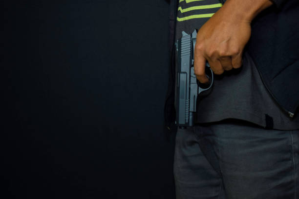 istock asian man holds a gun. Gun in his hand isolated on black background. 1180674596