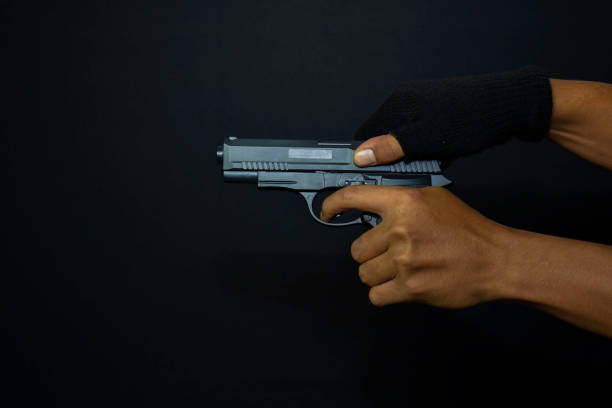 istock asian man holds a gun. Killed shooting his target isolated on black background. 1180674597