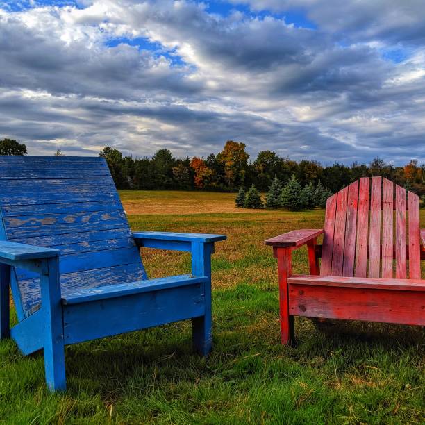 istock Blue and Red Adirondack chairs in a fall day 1180674598