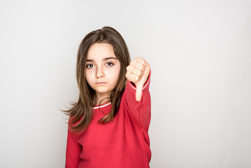 Unhappy little girl showing thumb down gesture