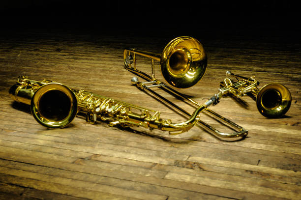 żółty mosiądz i instrumenty dęte - saksofon, puzon, trąbka na drewnianej scenie z podświetleniem - trombone musical instrument wind instrument brass band zdjęcia i obrazy z banku zdjęć