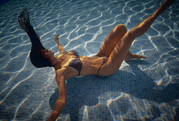 istock Woman posing inside of swimming pool on the depth 1180677425