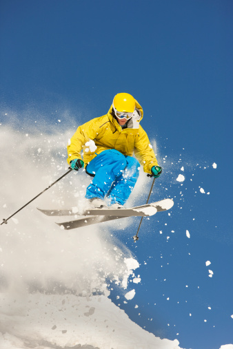 A young male skiing and making successful jump in the snow.