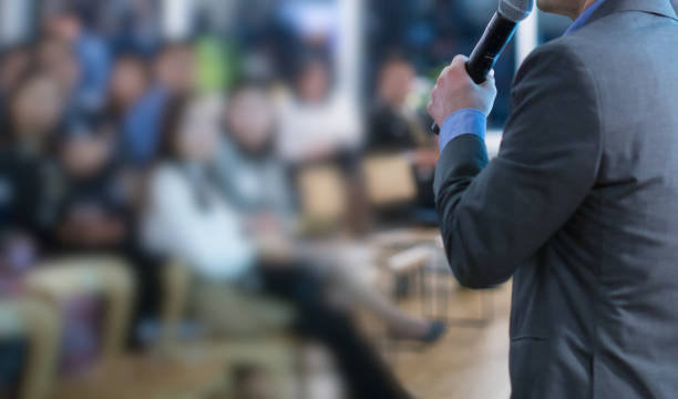 istock Tech speaker giving seminar to audience. Entrepreneurs in development workshop listen to presenter. Focus on mic of manager at speech in conference hall. Technology executive in professional lecture. 1180680228