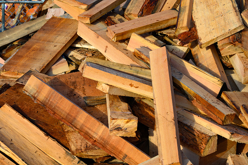 Wood piled for recycling. Scrap pile of wood for firewood. Wood waste from logging.