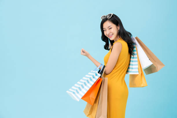 asiática shopaholic mujer llevando bolsas de compras de colores - women looking over shoulder people cute fotografías e imágenes de stock