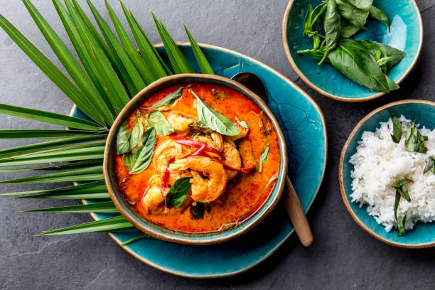 THAI SHRIMPS RED CURRY. Thailand Thai tradition red curry soup with shrimps prawns and coconut milk. Panaeng Curry in blue plate on gray background stock photo