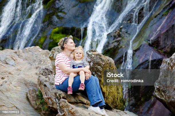 Cute Toddler Girl And Mother Sitting Near Water Cascade Of Powerscourt Waterfall The Highest Waterfall In Ireland In Co Wicklow Family Time Vacations With Small Children Woman And Baby Child Stock Photo - Download Image Now