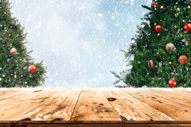 istock Top of empty wood table with beautiful Christmas tree and snowfall  backdrop 1180713197