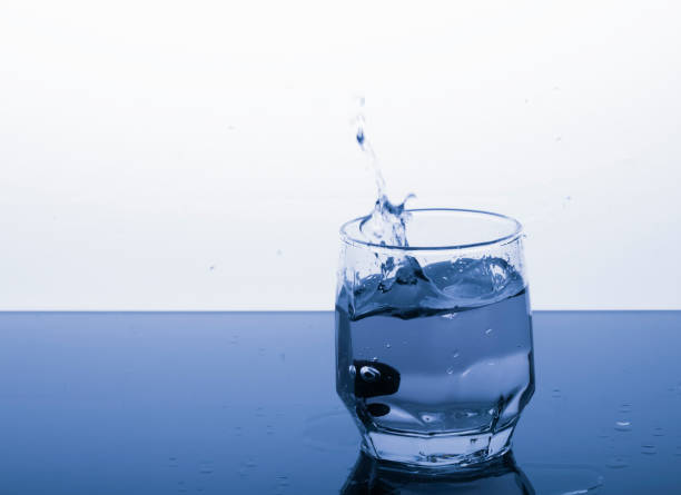 istock frozen cherries fall splashing into a glass of water 1180717688