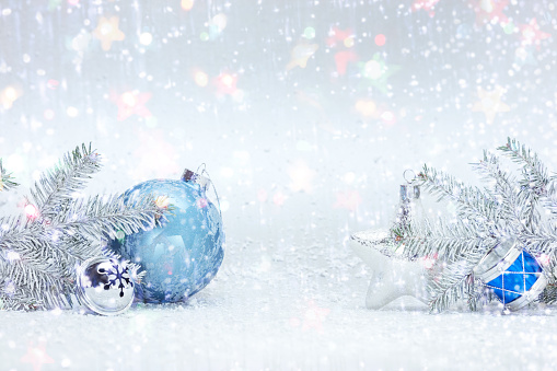 festive winter holidays composition on white snow with frosty christmas tree branches, decorative blue ball, silver glass star and drums toy