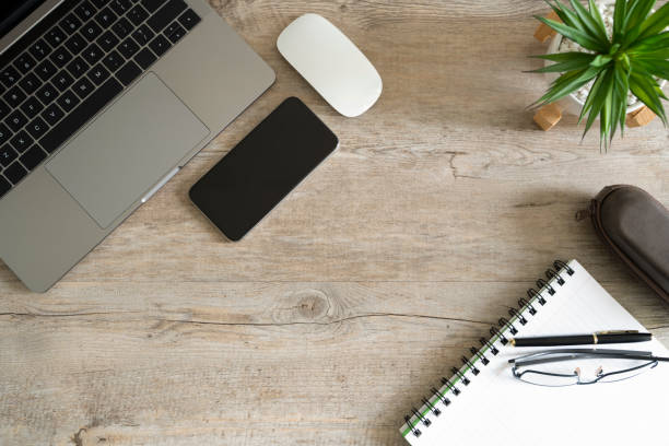istock Top View Laptop, Glasses, Empty Note Book, Smartphone And Headphones White Wooden Table 1180718621