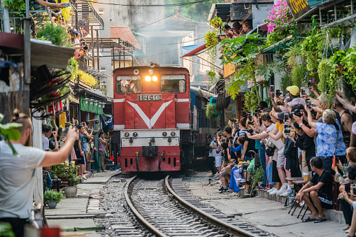 HANOI, VIETNAM - OCT 6, 2019 : View of train passing through a narrow street of the Hanoi Old Quarter. Tourists taking pictures of hurtling train. The Hanoi Train Street is a popular attraction.
