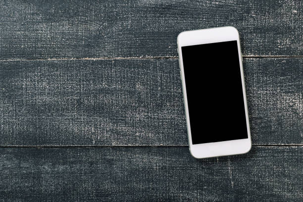istock White mobile phone on an office working dark wooden table. 1180720981