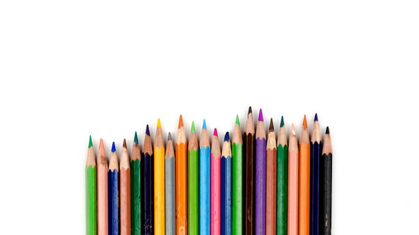 istock Old colored pencils. Some old colored pencils lined up on a white table 1180723134