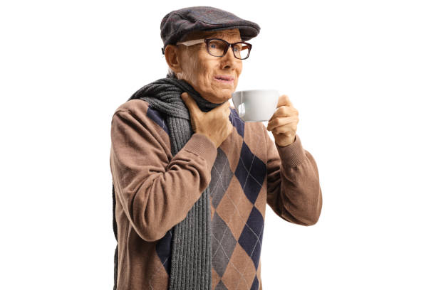 istock Senior man suffering from sore throat and having a hot tea 1180729113