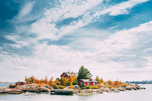Suomi o Finlandia. Hermosa cabaña de madera finlandesa roja en la costa de Rocky Island en verano noche soleada. Paisaje del lago o del río. Tiny Rocky Island Cerca de Helsinki, Finlandia photo