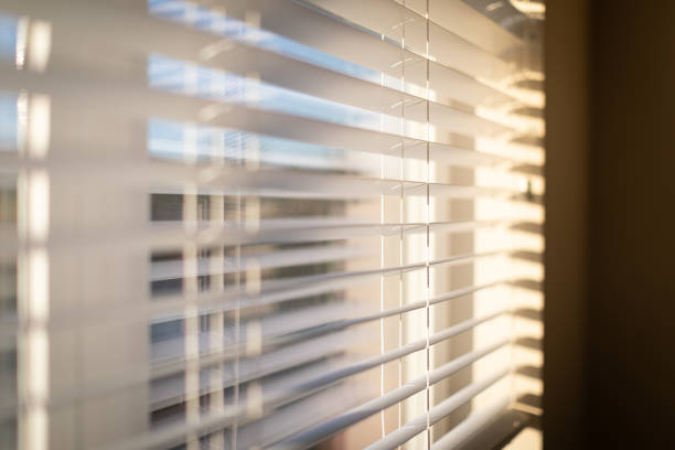 istock Sunlight coming through venetian blinds by the window 1180733884