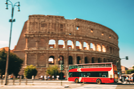 Rome, Italy. Colosseum. Red Hop On Hop Off Touristic Bus For Sightseeing In Street Near Flavian Amphitheatre. Famous World UNESCO Landmark. City Sightseeing Tour.