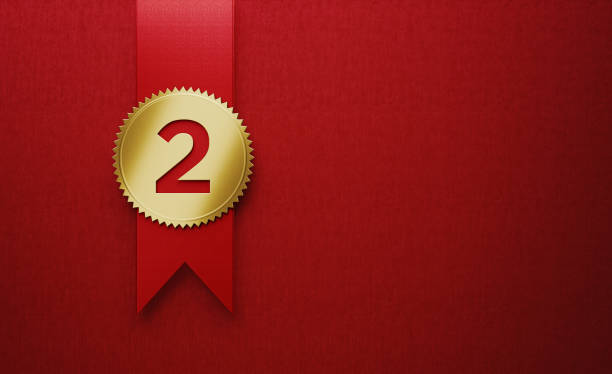 Gold cockade on red award ribbon on red background. Number two writes on the cockade. Vertical composition with copy space.