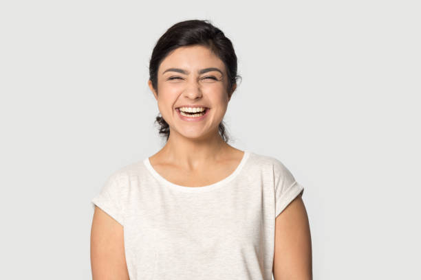 Overjoyed indian girl laugh posing on grey background Excited indian young woman in casual weat t-shirt posing isolated on grey studio background laughing, headshot portrait of overjoyed ethnic millennial girl feel happy pleased, humor concept indian woman laughing stock pictures, royalty-free photos & images