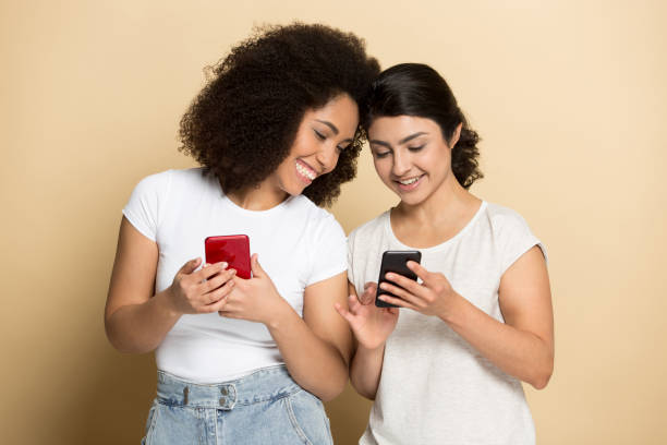 istock Smiling millennial multiethnic girlfriends laugh using cellphones 1180736083