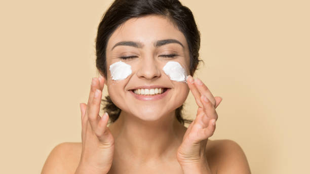 istock Smiling indian girl apply moisturizing face cream 1180736305