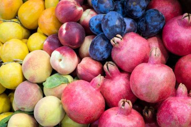 istock Pomegranate, plums, nectarines, bunch, peach at a showcase in a supermarket. 1180737891