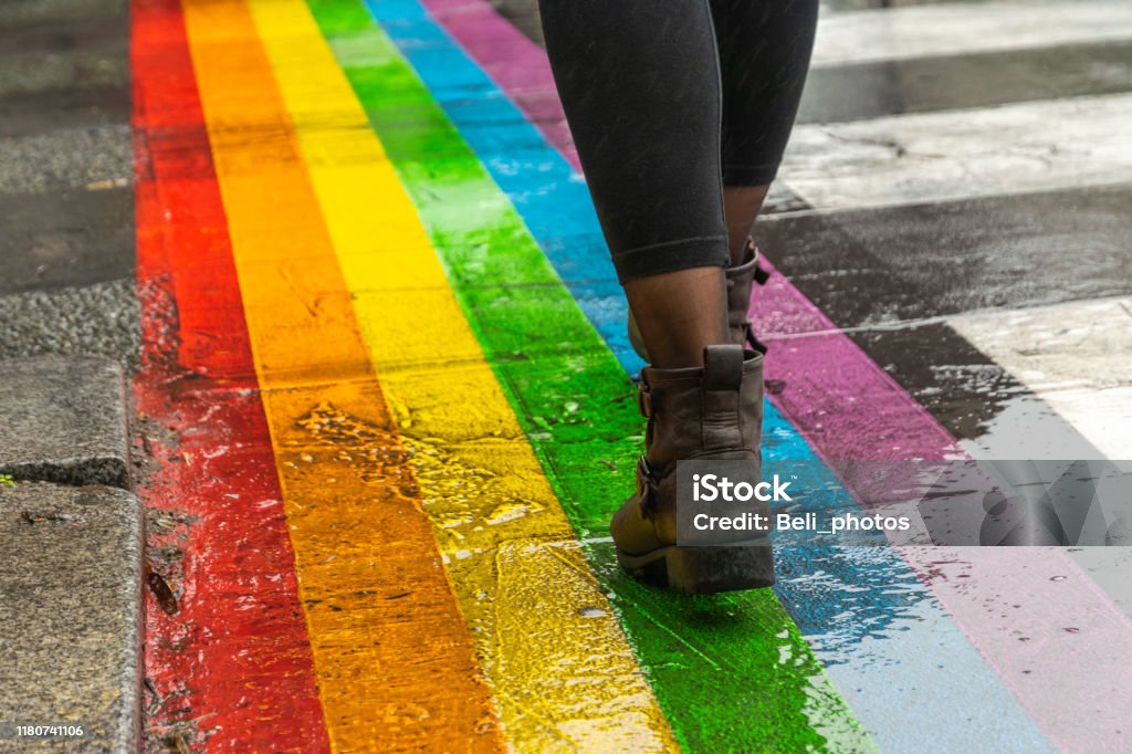 Legs walking on Gay rainbow crosswalk. Female legs walking on rainbow crosswalk in Gay parade. LGBTQIA Pride Event Stock Photo