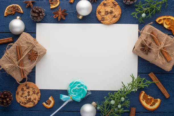 istock Christmas composition with white blank square card and fir branches and pine cones. On a blue wooden background, Flat lay, top view 1180748875